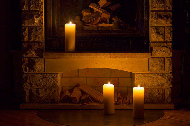 istock White large candles standing on the fireplace. 524026190