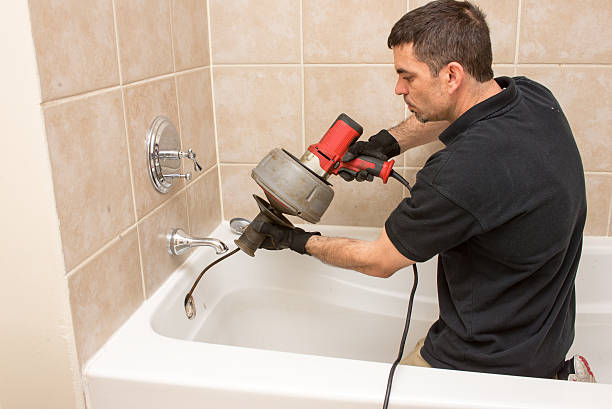 Plumber Working Plumber unclogging a tub drain with an electric auger. drain photos stock pictures, royalty-free photos & images
