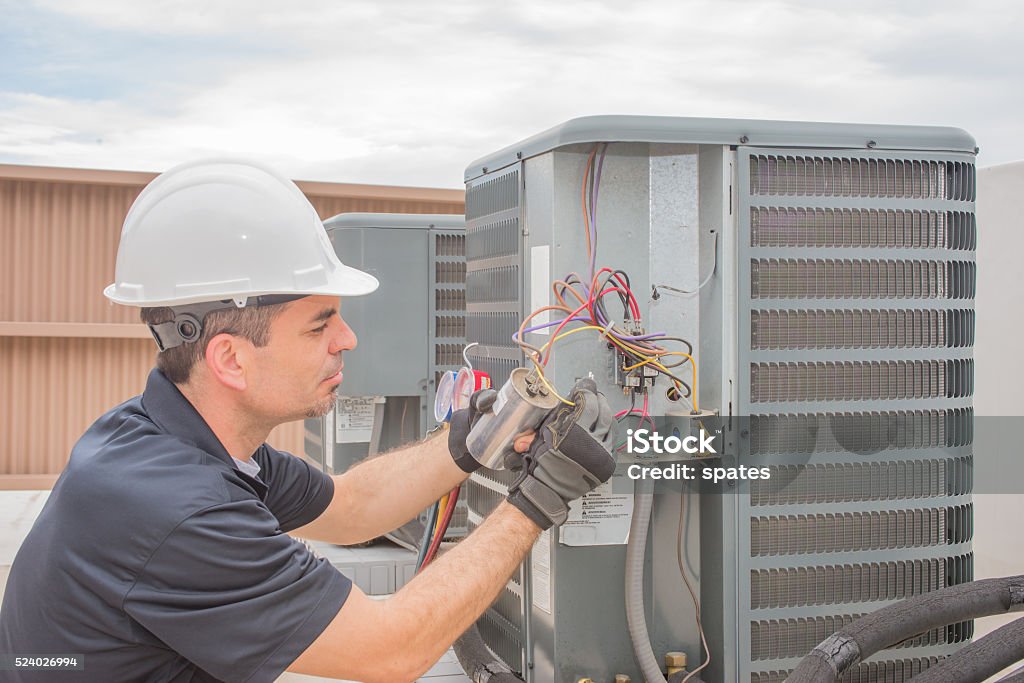 Technician and Capacitor HVAC technician working on a capacitor part for condensing unit. Air Conditioner Stock Photo