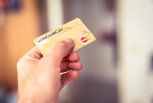 Florence, Italy - June 17, 2013: Man holding and paying with a master card credit card at the mall. Image taken indoors.