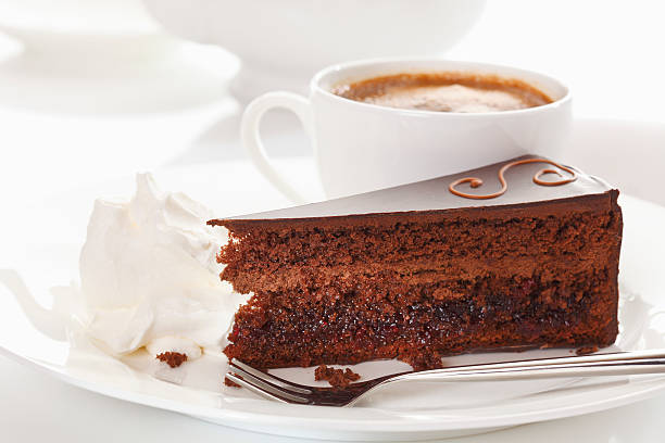 Slice of Sacher cake in plate with coffee stock photo