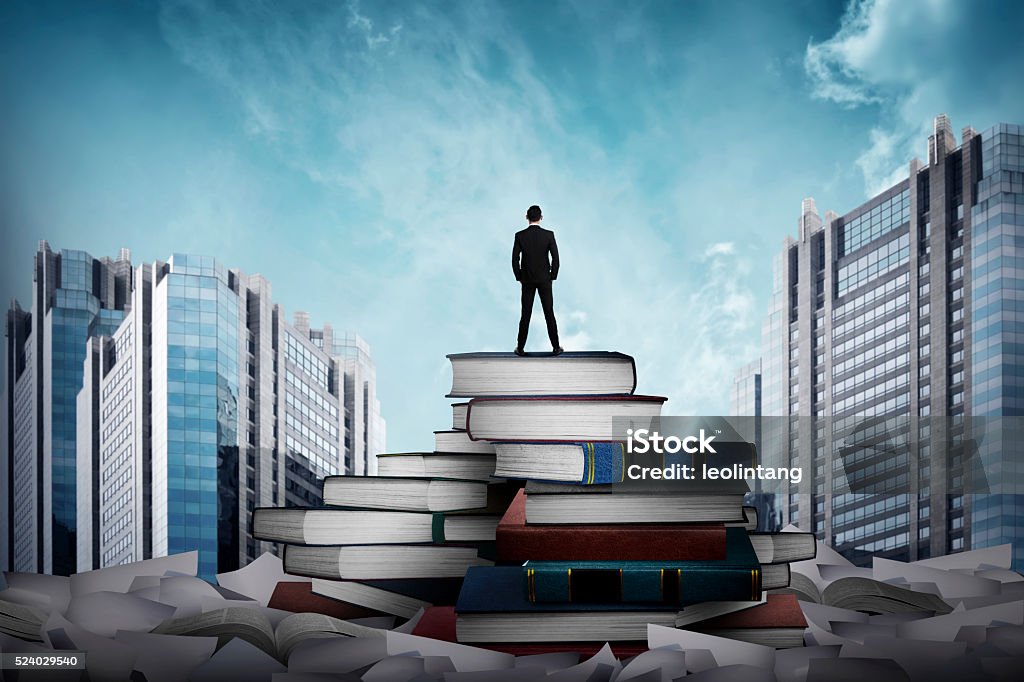 Business man standing on the top of books Business man standing on the top of books looking the city Large Stock Photo