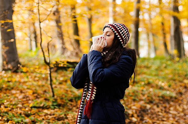 Woman sneezing in handkerchief at autumn stock photo