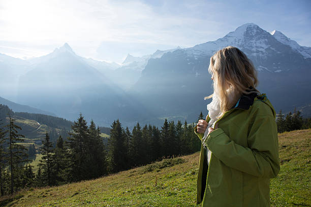 istock Woman looks out from meadow slope, mountains 524073095