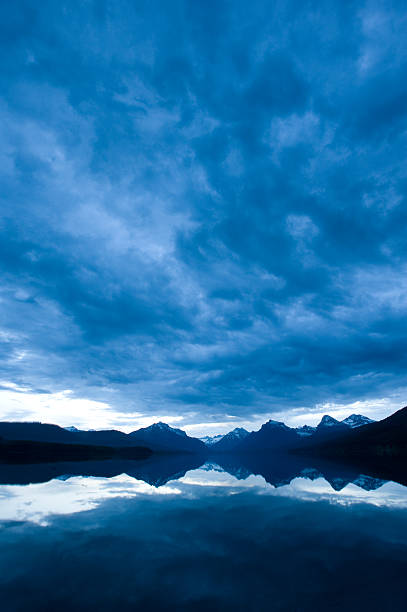 złowieszczy niebieski chmur odzwierciedlenie w lake - sunrise cloudscape us glacier national park vertical zdjęcia i obrazy z banku zdjęć