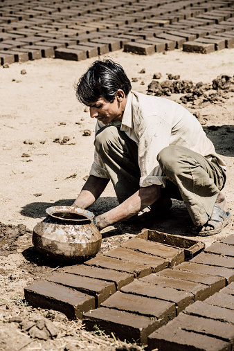 Rajasthan, India - March 13, 2014: Worker making clay mud bricks outdoors in rural Rajasthan.