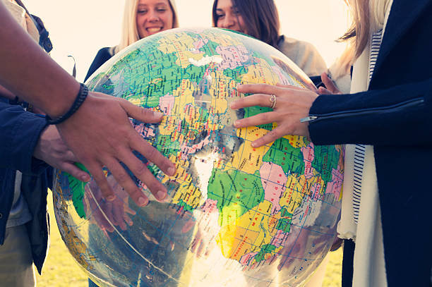 grupo de jovens segurando um globo do mundo - adolescence teenager globe map - fotografias e filmes do acervo