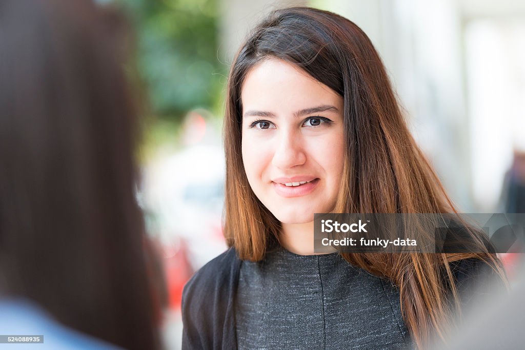 Turkish girl talking with her friend at a cafe A young adult woman is listening her friend enthusiastically at a cafe. She is giving a firm smile. Copy space on left. 20-24 Years Stock Photo