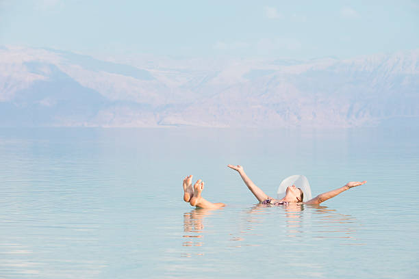 Woman floating in Dead Sea. Young woman enjoying floating at dead sea Israel, feeling wonderful with arms outstretched. dead sea stock pictures, royalty-free photos & images