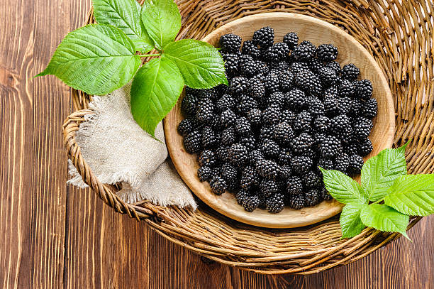 Blackberry in wooden bowl in rustic basket stock photo