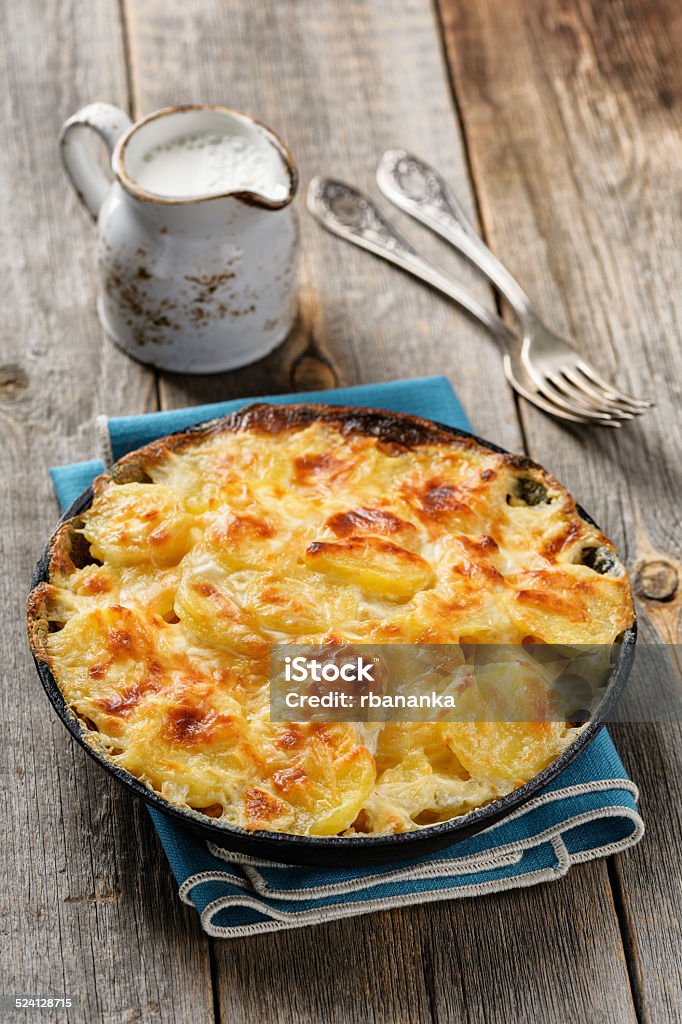 Potato gratin in casserole with cream and cheese Potato gratin in casserole with cream and cheese on grey wooden table Gratin Stock Photo