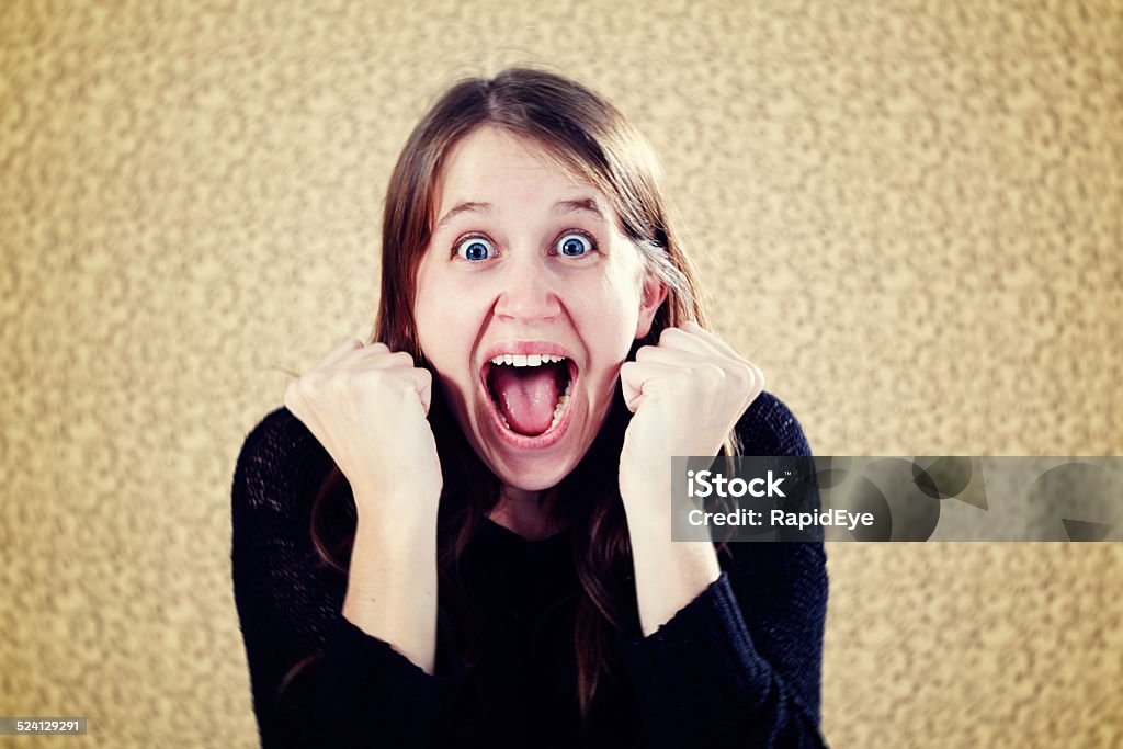 Excited young woman clenches fists, yells in delight A cute, extremely excited young woman clenches her fists and yells happily. Copy space. 20-29 Years Stock Photo
