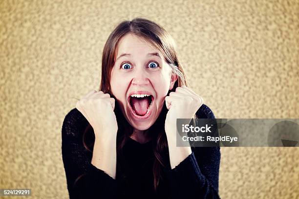 Excited Young Woman Clenches Fists Yells In Delight Stock Photo - Download Image Now