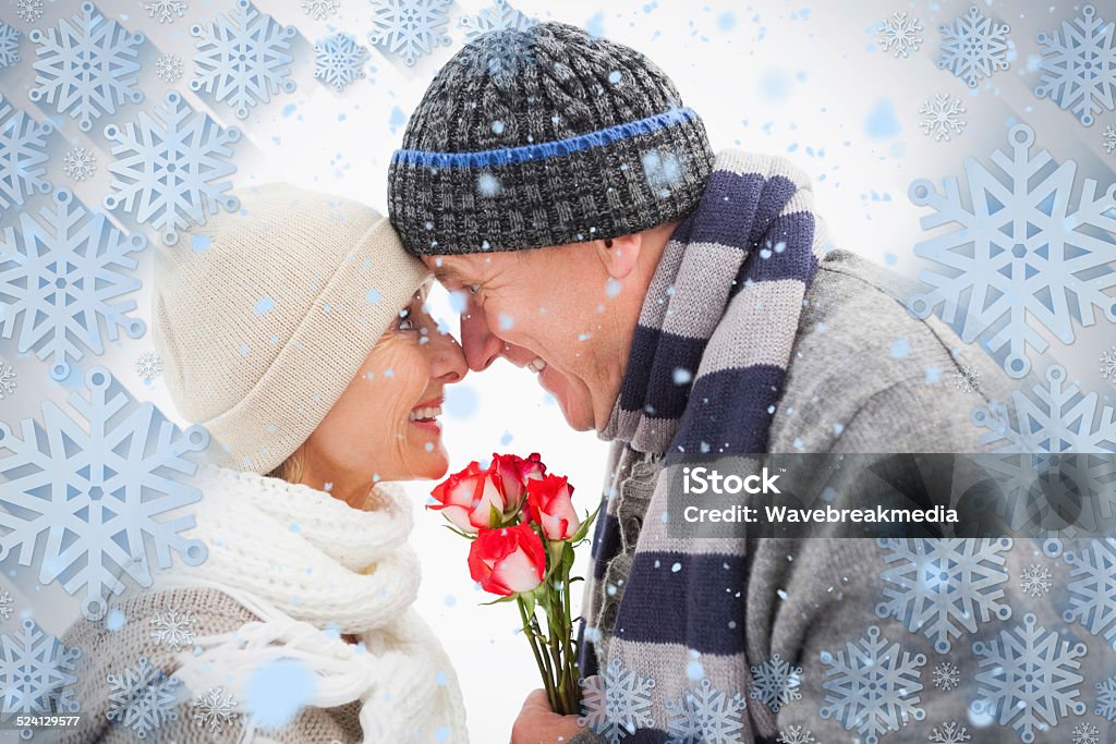 Feliz pareja madura en ropa de invierno con rosas - Foto de stock de 50-54 años libre de derechos