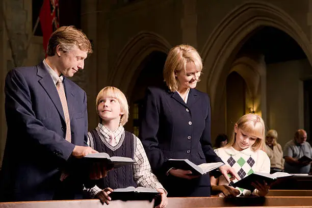 Photo of Family Standing and Praying in Church