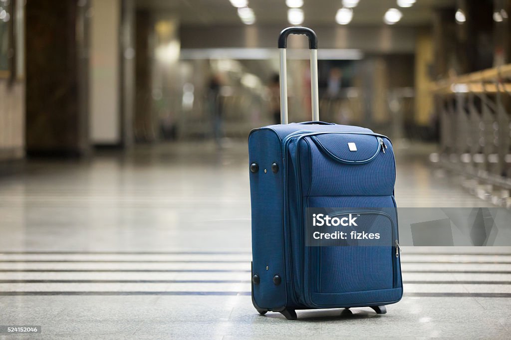 Blue suitcase at airport Large blue wheeled suitcase standing on the floor in modern airport terminal. Copy space Suitcase Stock Photo