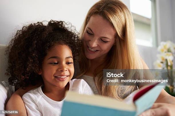 Caucasian Mum And Smiling Black Daughter Read In Bed Closeup Stock Photo - Download Image Now