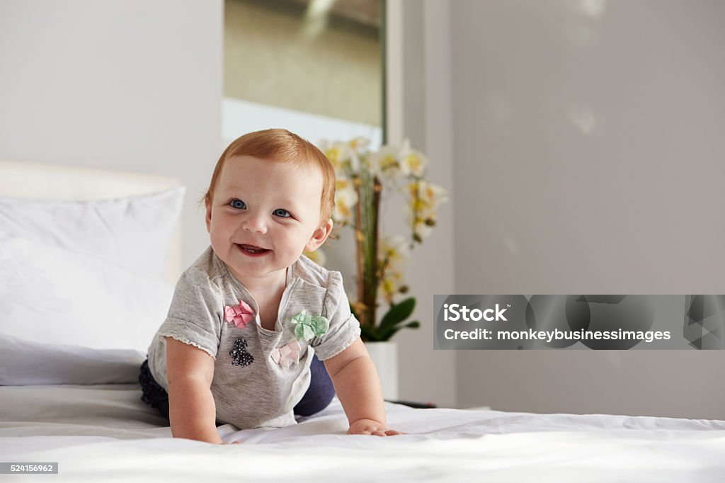 Um Bebê Menina feliz Agachamento com uma cama king-size, espaço para texto à direita - Foto de stock de Aconchegante royalty-free