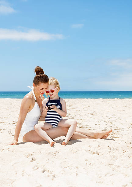 istock Mother and child at beach looking on photos in camera 524161298