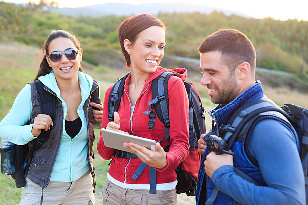 istock Cheerful young people hiking and using digital tablet 524162718