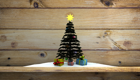 Stock photo showing a beautiful Christmas village display, which features numerous illuminated houses. The houses have been placed on artificial grass and sprinkled with fake snow to create a snowy scene, on top of a chest of drawers, complete with a forest of plastic spruce trees.