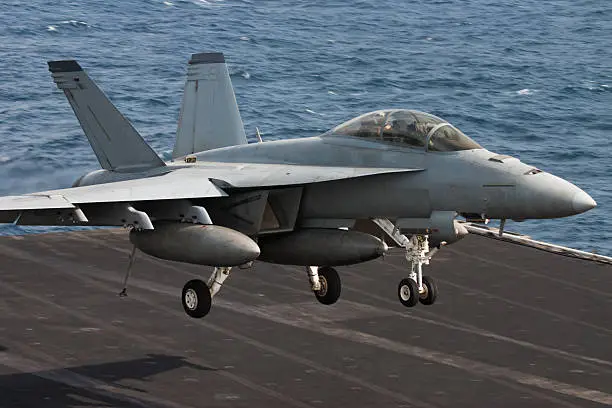 A United States Navy fighter plane landing on the aircraft carrier.