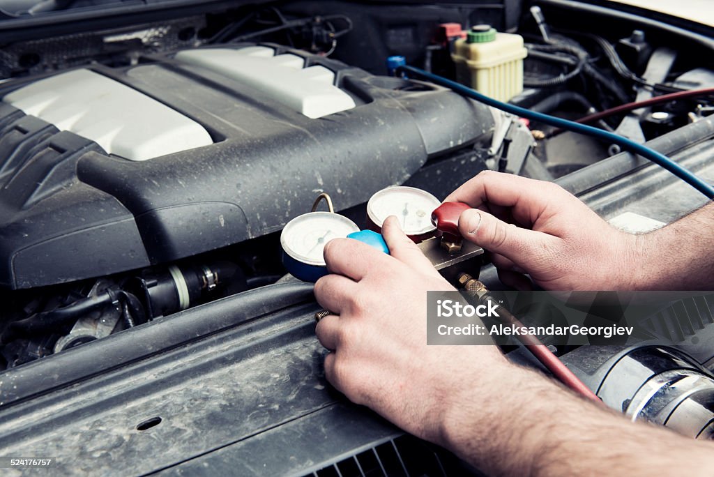 Recharging Car with Freon Automotive Specialist Adjusting or Recharging Car with Freon. Freon Pump Charges AC Unit for car air conditioning system. Air Conditioner Stock Photo