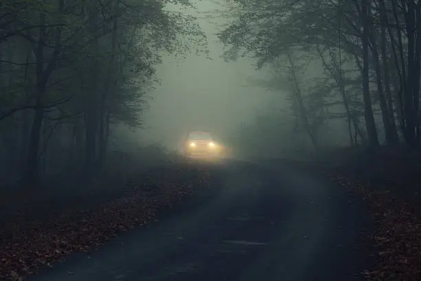 spooky scene with headlights  apparition in deep fog at night.