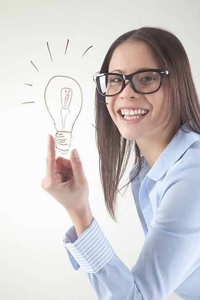 istock Business woman with drawn light bulb on whiteboard smiling 524199645
