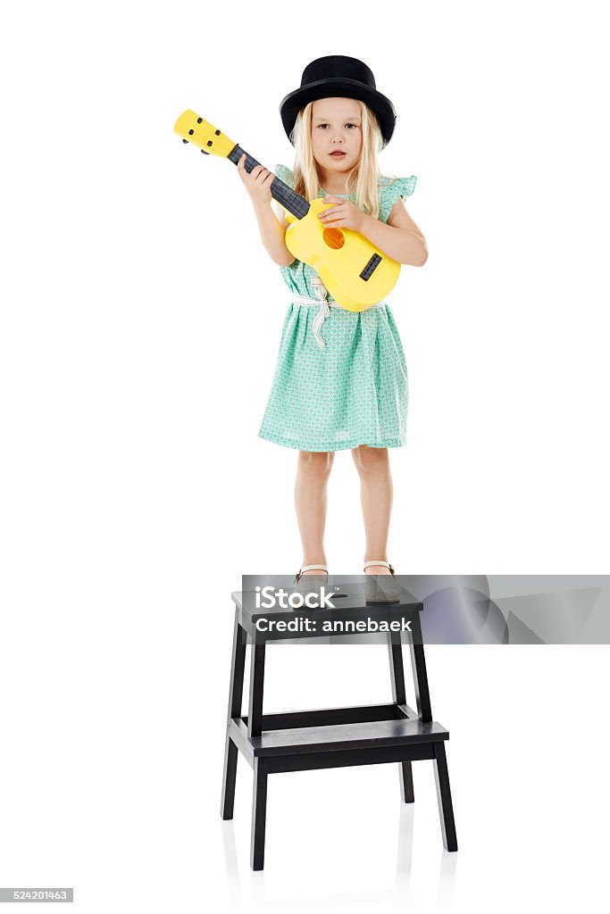 Jazzy junior Studio shot of a cute little girl playing with her toy guitar against a white background Activity Stock Photo