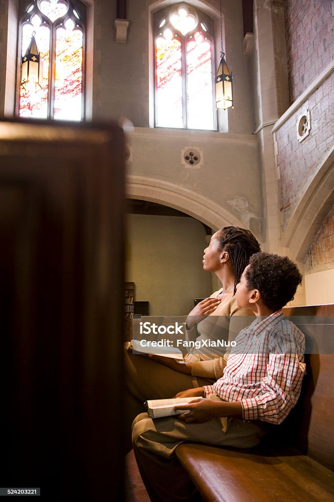 Mother and Son Praying from Bible in Church Church Stock Photo