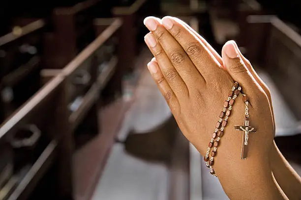 Hands Praying in Church With Rosary