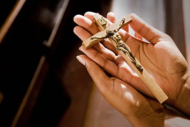 Photo of Hands Praying in Church With Cross