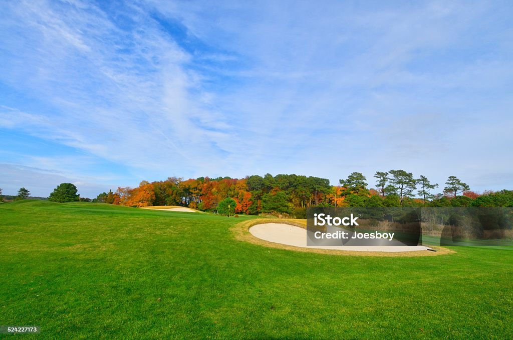 Golf Course In Fall A local public golf course with some colorful trees behind the green on a bright fall day on Maryland's Eastern Shore near Ocean City, Watch out for the trap. Golf Course Stock Photo