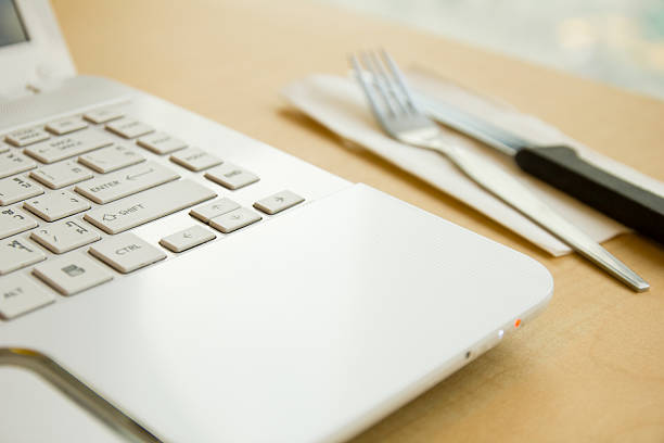 istock White laptop with fork and knife on wood table. 524230209