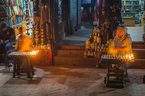 kathmandu, Nepal - 5th November 2014: Yak fat candles sold as devotional Buddhist offerings to worshippers and pilgrims by pavement traders illuminated at night beside the dome of Boudhanath Stupa, the historic UNESCO World Heritage Site in the heart of Kathmandu, Nepal's vibrant capital city.