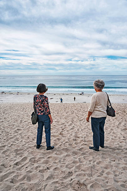 Carmel, California, USA - November 18, 2014: These two senior Japanese Ladies are looking at the people and the beach in Carmel Central California this beach is at the end of Ocean Street and seems to be very popular this november morning with heavy clouds overhead makes this a very beautiful scene.