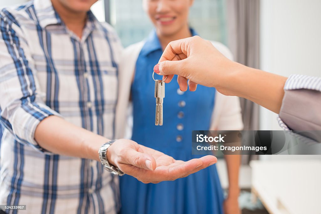 Giving keys Hands of estate agent giving keys to the couple House Stock Photo