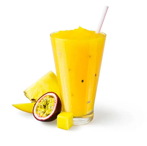 A pineapple, passionfruit, and mango smoothie in a generic glass on a white background with a garnish of mangos, a pineapple wedge, and half a passionfruit on the side.