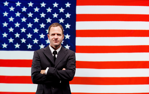 Businessman standing in front of American flaghttp://www.twodozendesign.info/i/1.png