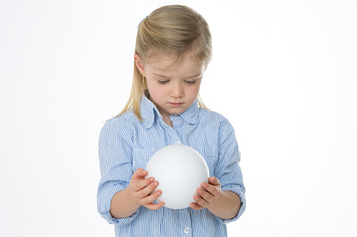 little girl curiously looking at a white ball