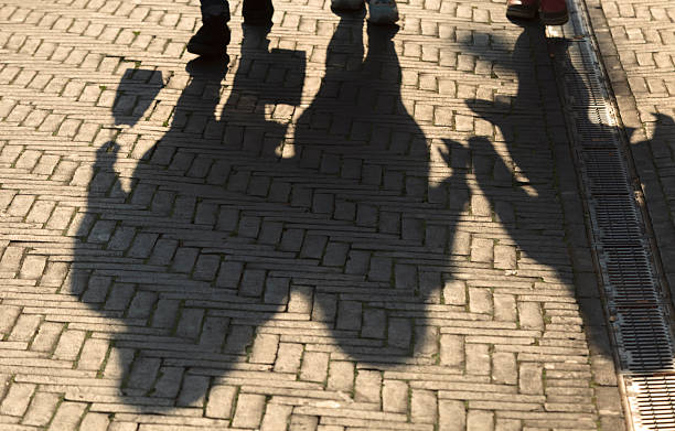 istock sun casting shadow over three people walking on the street 524259601