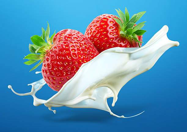 istock Two strawberries falling into milk splash isolated on blue background 524260315