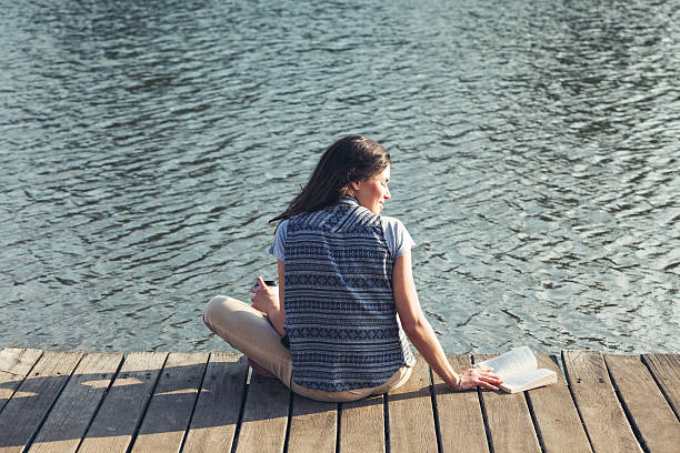 istock girl with reading a book on a pier 524285317