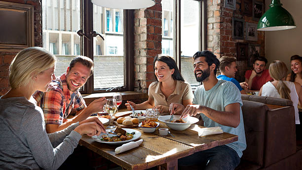 Friends Enjoying a Meal Group of friends enjoying a meal in a restaurant. pub food stock pictures, royalty-free photos & images