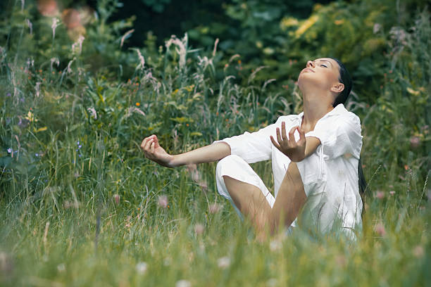 istock Beautiful young woman meditating on field. 524299217