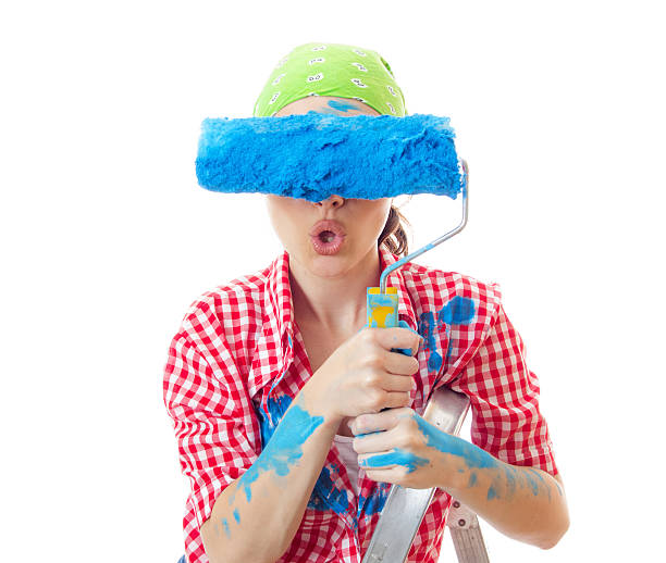 Amazed woman painter holding roller over her eyes stock photo