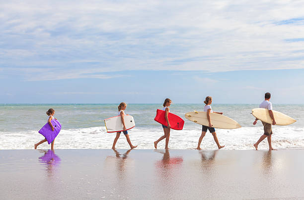 família pais menina crianças com pranchas de surf na praia - women sea cheerful surfing imagens e fotografias de stock