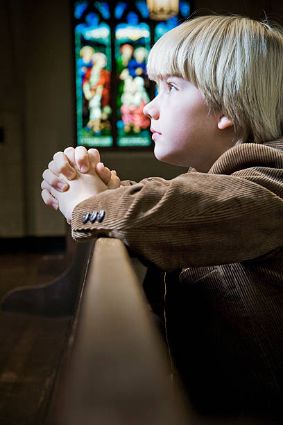 istock Young Boy Kneeling and Praying in Church 524327609