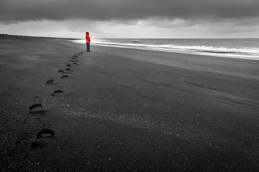A woman is watching the waves on a black sand beach in the south of Iceland
